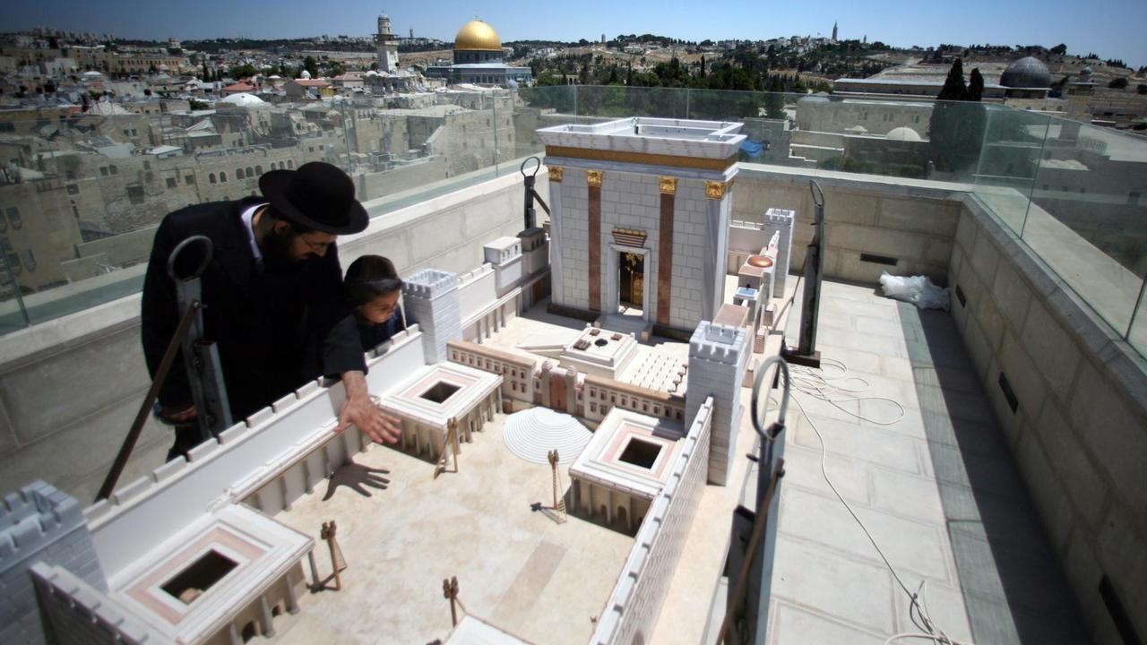 Ein ultra-orthodoxer jüdischer Mann zeigt seinem Sohn das Modell des Zweiten Tempels, der von den Römern zerstört wurde. Im Hintergrund ist der Tempelberg zu sehen.