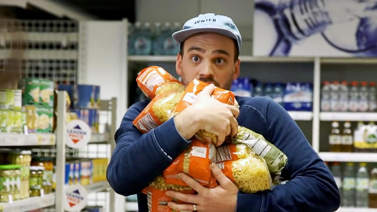 Ein junger Mann im Supermarkt versucht so viele Pasta Packungen wie möglich in seinen Armen zu trasportieren. Ein junger Mann im Supermarkt versucht so viele Pasta Packungen wie möglich in seinen Armen zu trasportieren.