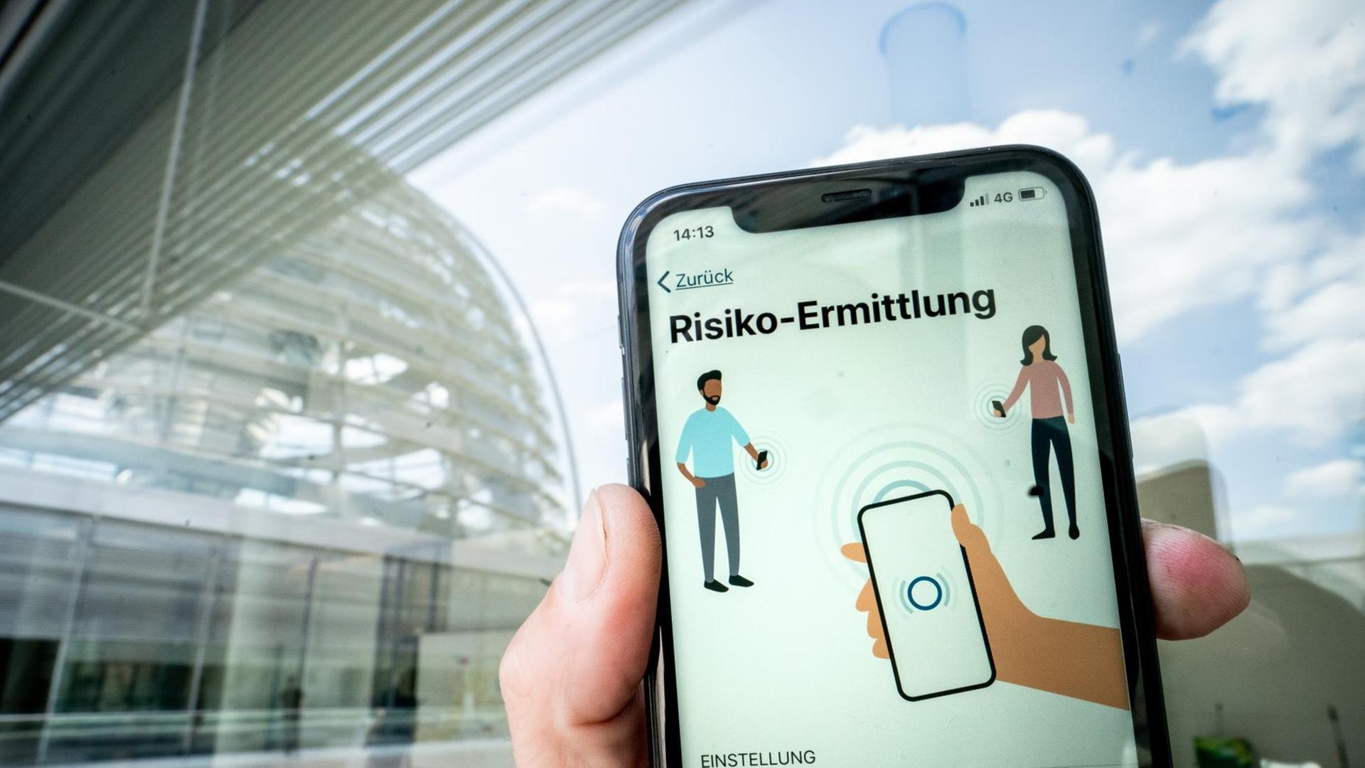 Die Corona-Warn-App mit der Seite zur Risiko-Ermittlung ist im Display eines Smartphone vor der Kuppel des Reichstags zu sehen. Die Corona-Warn-App mit der Seite zur Risiko-Ermittlung ist im Display eines Smartphone vor der Kuppel des Reichstags zu sehen.