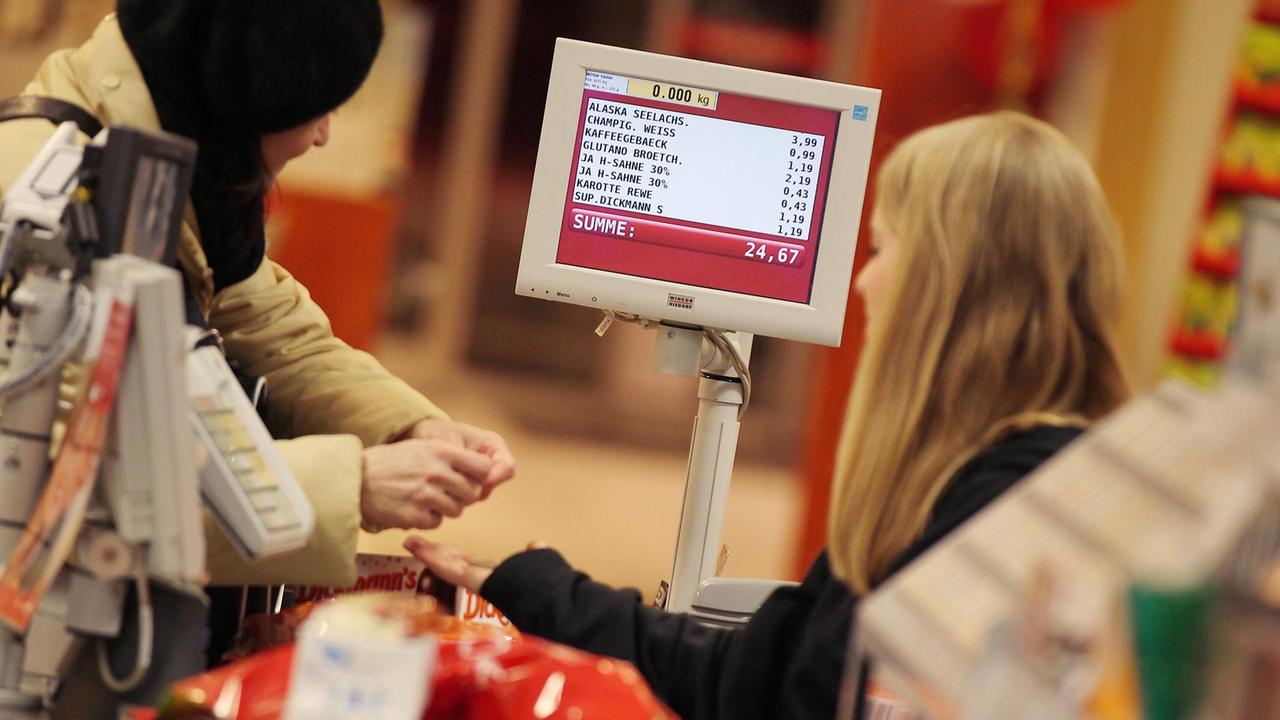 Eine Kassiererin nimmt am in einem Supermarkt das Geld einer Kundin entgegen. Eine Kassiererin nimmt am in einem Supermarkt das Geld einer Kundin entgegen.