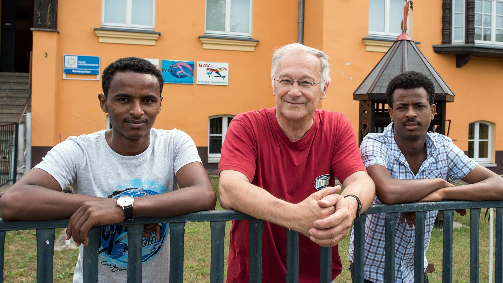 Der Bundestagsabgeordnete Martin Patzelt (CDU) und die beiden Flüchtlinge aus Eritrea Haben und Awet am Zaun des Gemeinde- und Vereinshauses in Briesen im Landkreis Oder-Spree (Brandenburg). Sie lehnen sich über ein Geländer und schauen in die Kamera. Der Bundestagsabgeordnete Martin Patzelt (CDU) und die beiden Flüchtlinge aus Eritrea Haben und Awet am Zaun des Gemeinde- und Vereinshauses in Briesen im Landkreis Oder-Spree (Brandenburg). Sie lehnen sich über ein Geländer und schauen in die Kamera.