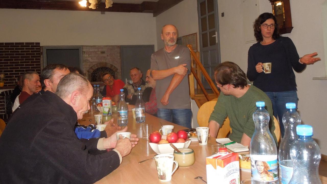 An einem langen Tisch sitzen Menschen zusammen. An einem langen Tisch sitzen Menschen zusammen.