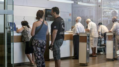 In der griechischen Hauptstadt Athen warten einige Menschen am Tag der Wiedereröffnung nach dreiwöchiger Schließung der Banken vor den Schaltern einer Filiale, aufgenommen am 20.7.2015.