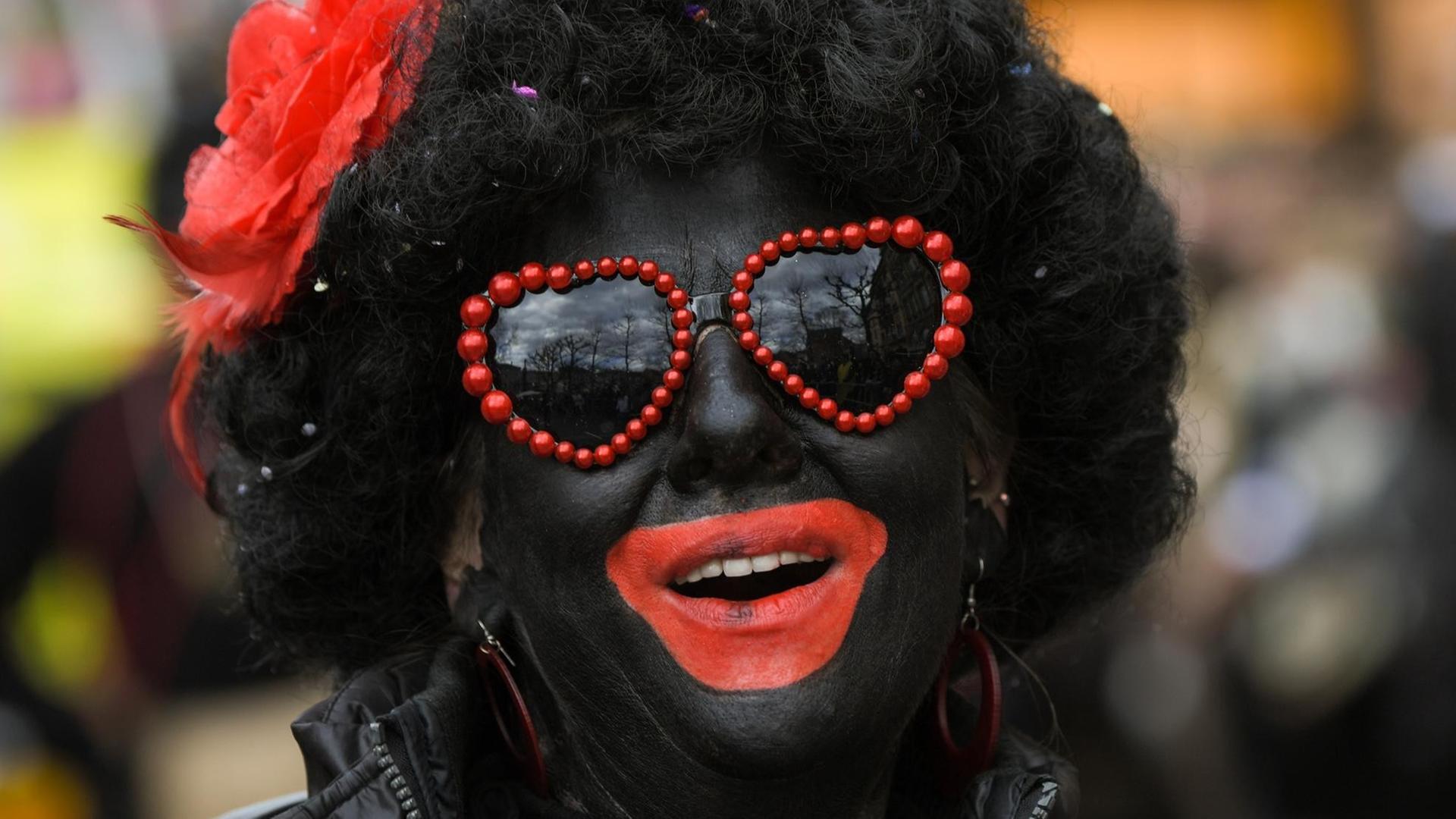 Ein Närrin hat sich im Gesicht am 27.02.2017 in Mainz (Rheinland-Pfalz) komplett schwarz geschminkt. Der Rosenmontagsumzug ist der alljährliche Höhepunkt der Mainzer Fastnacht die in diesem Jahr unter dem Motto "De Dom gehört zu Meenz am Rhoi wie Fassenacht, Weck, Worscht un Woi" steht. Foto: Andreas Arnold/dpa | Verwendung weltweit Ein Närrin hat sich im Gesicht am 27.02.2017 in Mainz (Rheinland-Pfalz) komplett schwarz geschminkt. Der Rosenmontagsumzug ist der alljährliche Höhepunkt der Mainzer Fastnacht die in diesem Jahr unter dem Motto "De Dom gehört zu Meenz am Rhoi wie Fassenacht, Weck, Worscht un Woi" steht. Foto: Andreas Arnold/dpa | Verwendung weltweit