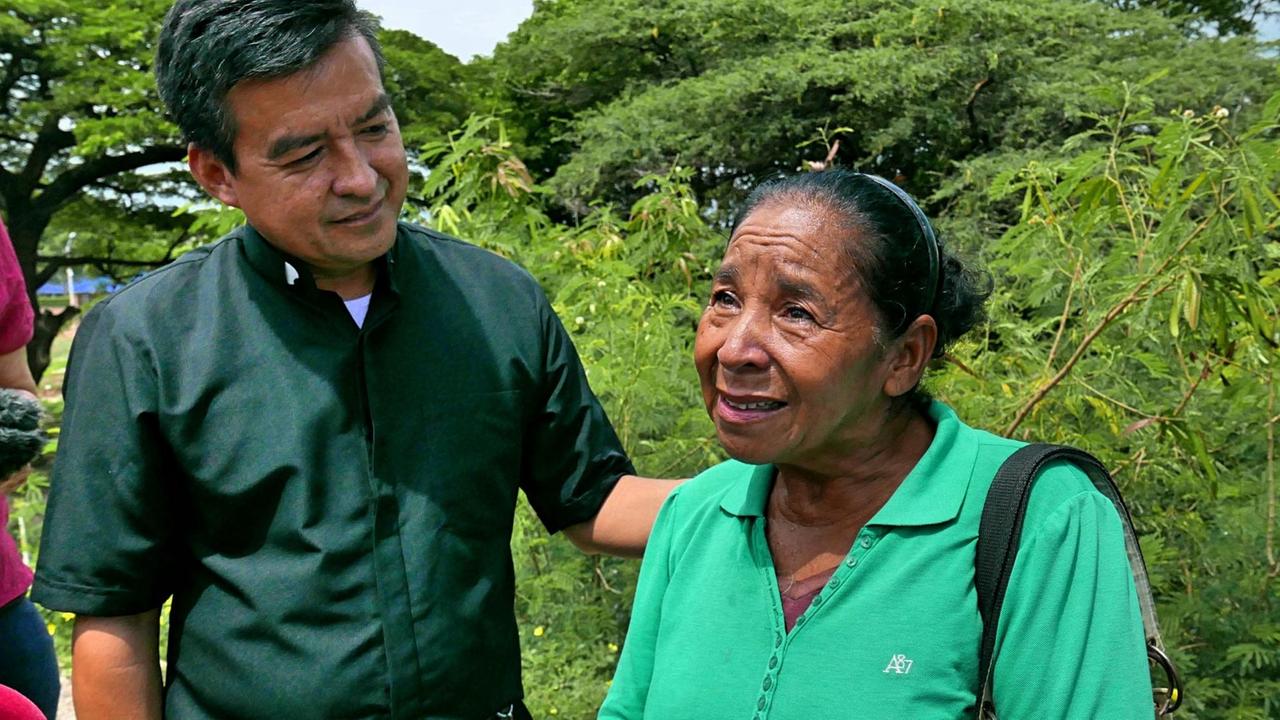 Elbert Roja, Pfarrer in Cúcuta legt seinen linken Arm beschützend um Maria.