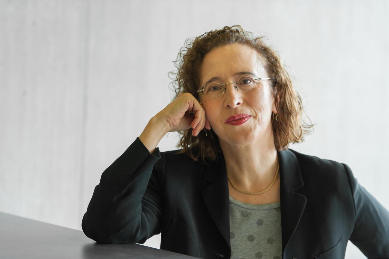 Die Philosophin Monika Betzler, den Kopf auf die Hand gestützt und in die Kamera lächelnd. Die Philosophin Monika Betzler, den Kopf auf die Hand gestützt und in die Kamera lächelnd.