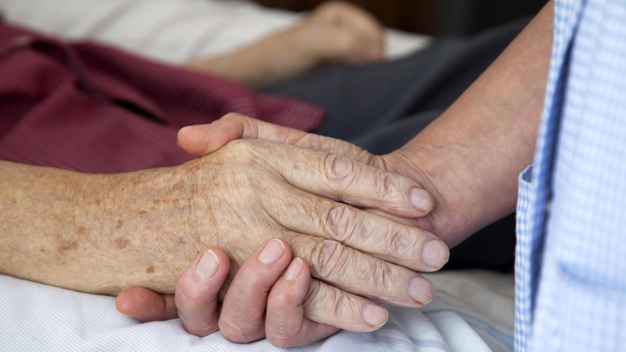 15.07.2010, Nordrhein-Westfalen, Deutschland - Hospiz. Die Hand einer Pflegerin haelt die Hand eines sterbenden Mannes. (QF, ältere, älterer, berühren, Berührung, bettlägerig, europäisch, Fürsorge, fürsorglich, Hände, häusliche Pflege, Menschenwürde, menschenwürdiges Sterben, Nähe, trösten) 00X110715D001.JPG MODEL RELEASE: YES,RELEASE: 15.07.2010, Nordrhein-Westfalen, Deutschland - Hospiz. Die Hand einer Pflegerin haelt die Hand eines sterbenden Mannes. (QF, ältere, älterer, berühren, Berührung, bettlägerig, europäisch, Fürsorge, fürsorglich, Hände, häusliche Pflege, Menschenwürde, menschenwürdiges Sterben, Nähe, trösten) 00X110715D001.JPG MODEL RELEASE: YES,RELEASE:
