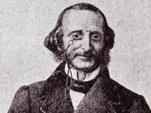 Ein Porträt von Jacques Offenbach. Er trägt einen langen Mantel, auf der Nase seinen Zwicker.