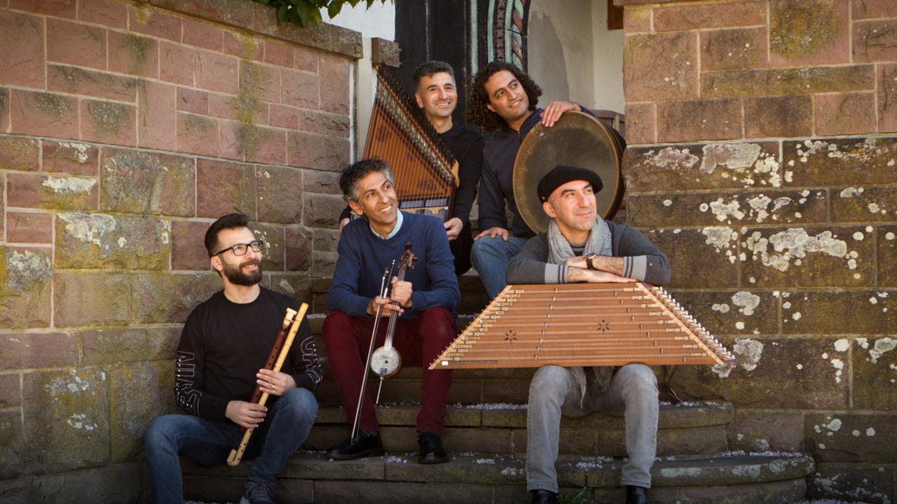 Die fünf Musiker sitzen mit ihren Instrumenten auf einer Treppe zu einem alten Gebäude Die fünf Musiker sitzen mit ihren Instrumenten auf einer Treppe zu einem alten Gebäude
