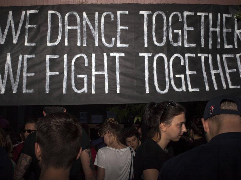 Demonstranten vor einem Banner mit der Aufschrift "We dance together, we fight together" während eines Protest in der Nähe der Botschaft Georgiens in Warschau