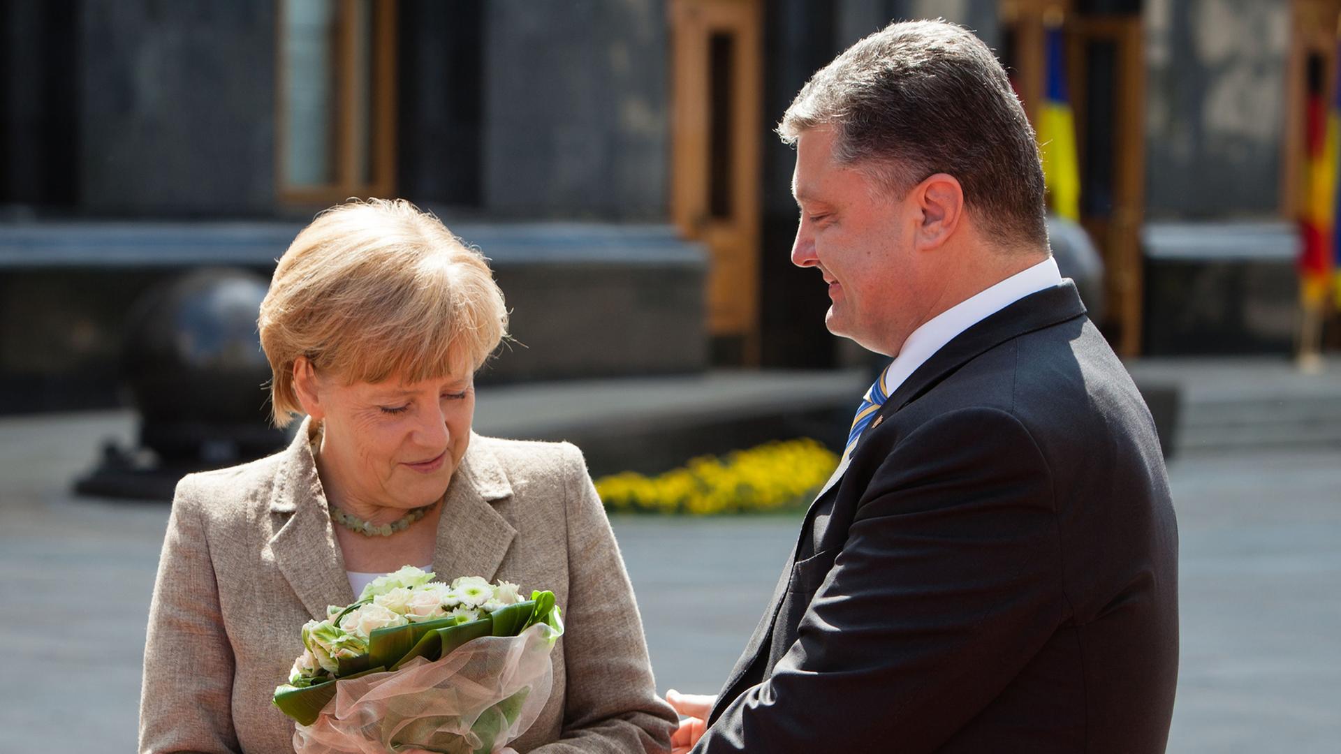 Der ukrainische Präsident Petro Poroschenko begrüßt Bundeskanzlerin Angela Merkel in Kiwe mit Blumen