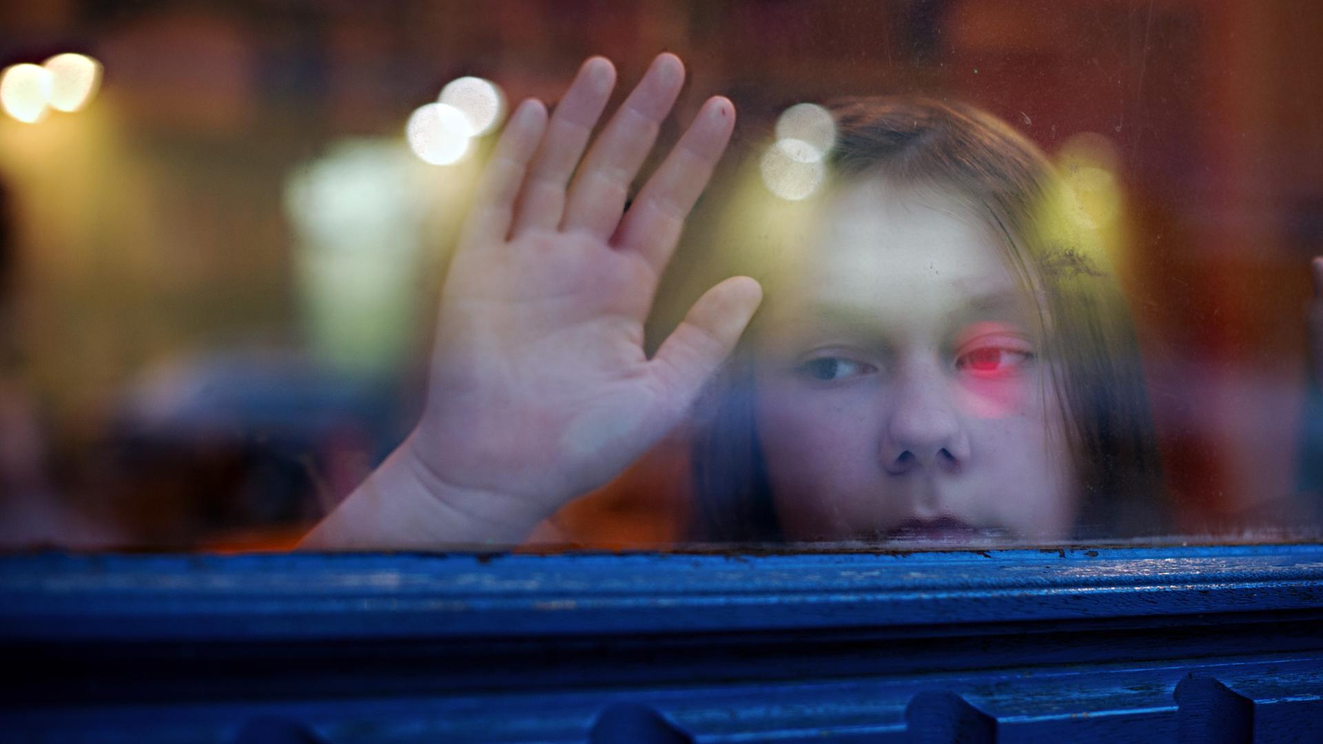 Ein junges Mädchen blickt am 24.01.2014 in Berlin aus einem Fenster.