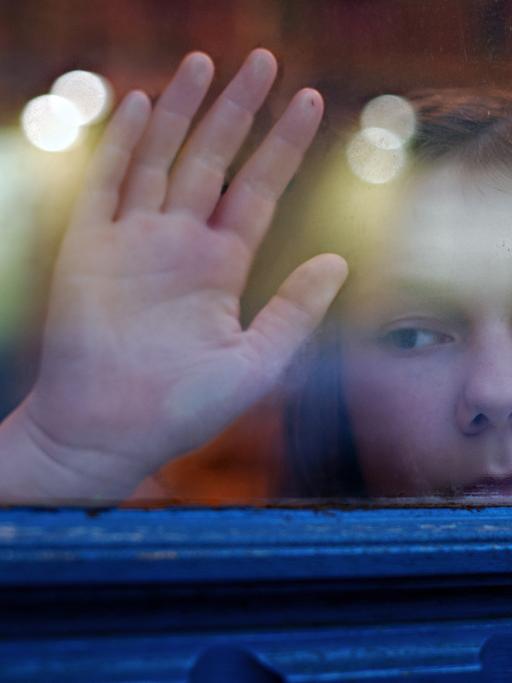 Ein junges Mädchen blickt am 24.01.2014 in Berlin aus einem Fenster.