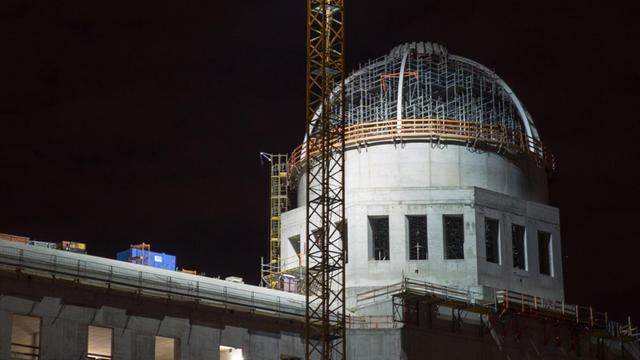 Die Kuppel des Rohbaus des Berliner Schlosses, das den Namen Humboldt-Forum trägt, in Berlin. Es ist Nacht, im Vordergrund ein Baukran.