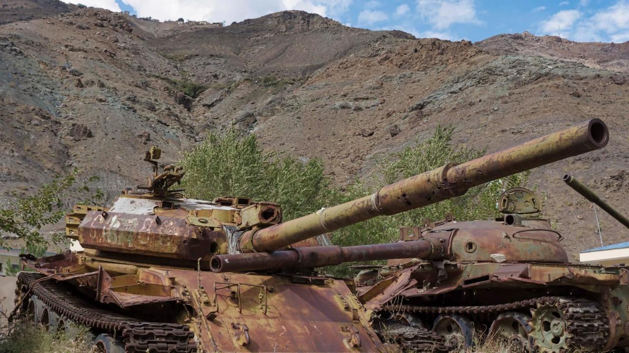 Aufgegebene und verrostete Panzer stehen in der afghanischen Landschaft
