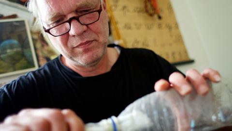 Der Künstler Joachim Römer zieht in Köln einen Brief aus einer Flasche.