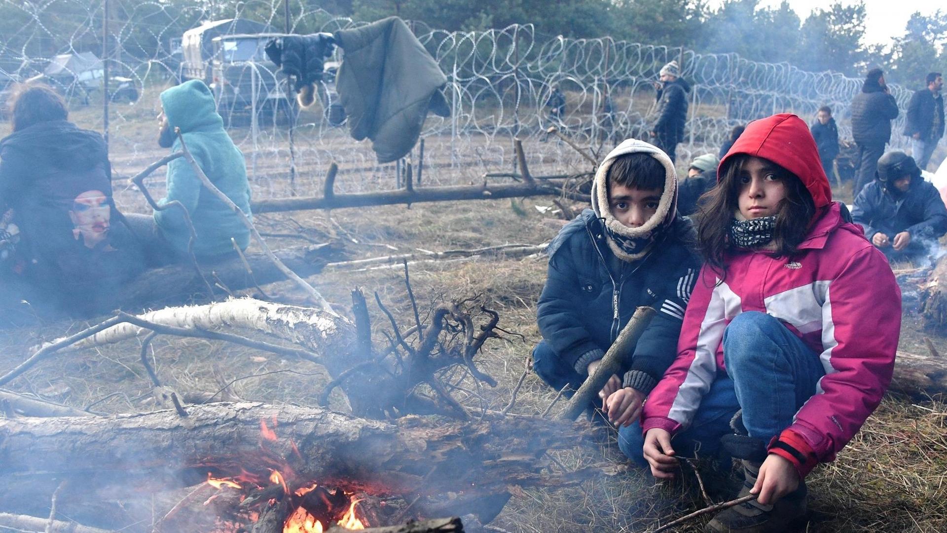 Kinder an einem Feuer an der Grenze zwischen Polen und Belarus. Kinder an einem Feuer an der Grenze zwischen Polen und Belarus.