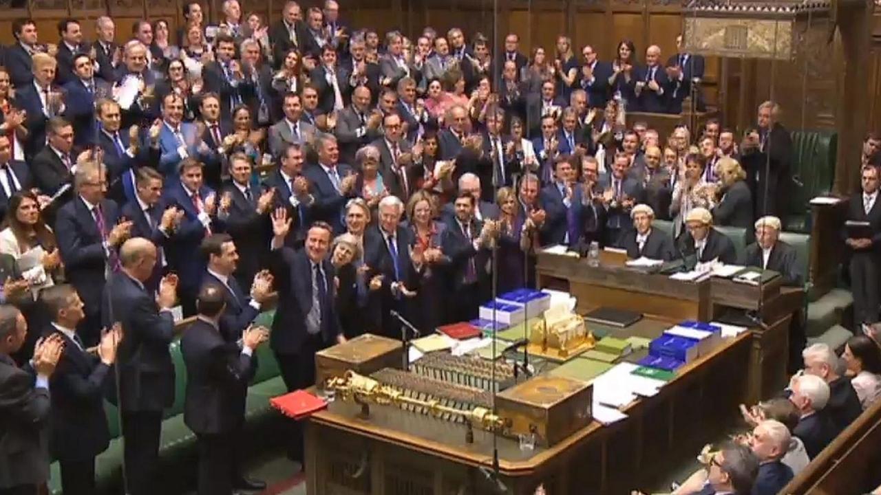 Das Bild zeigt das vollbesetze applaudierende Unterhaus; Cameron steht am Rednerpult und winkt den Abgeordneten zu. Das Bild zeigt das vollbesetze applaudierende Unterhaus; Cameron steht am Rednerpult und winkt den Abgeordneten zu.