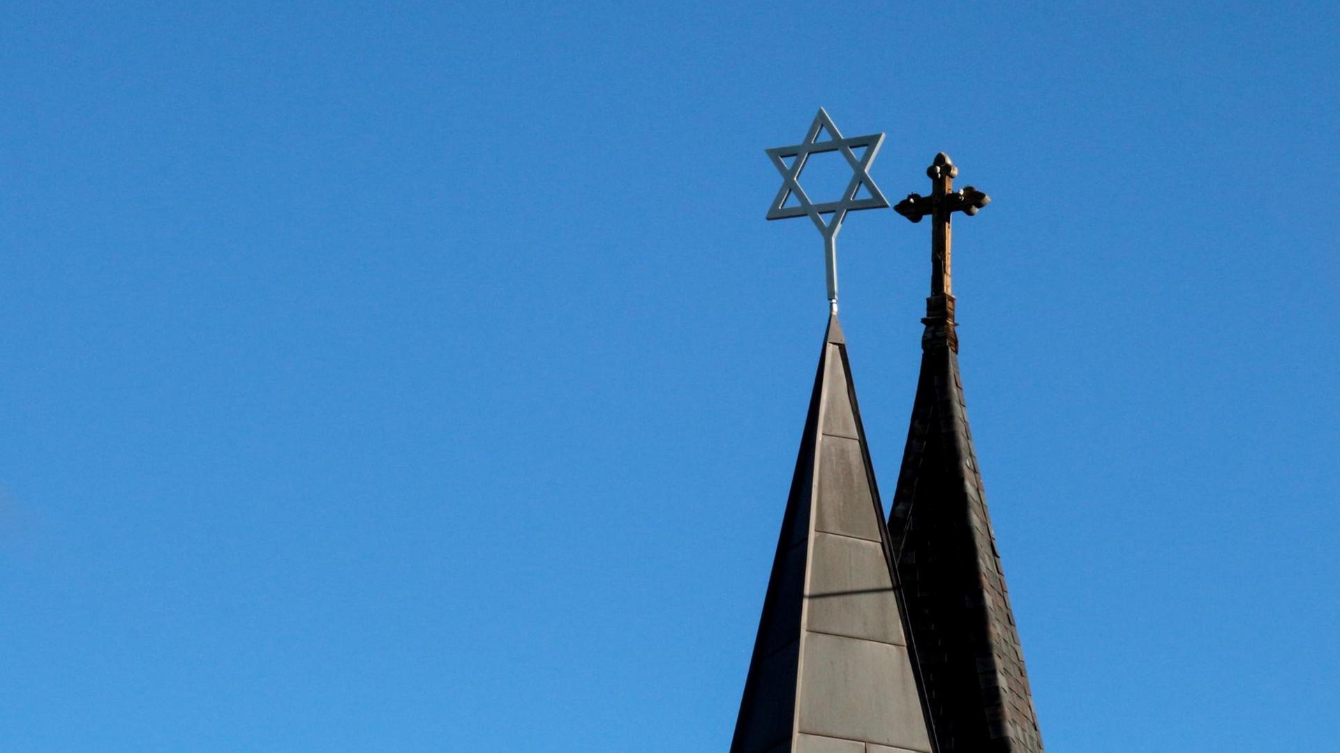 Auf zwei nebeneinander stehenden Türmen steht ein Kreuz bzw. ein Davidstern Auf zwei nebeneinander stehenden Türmen steht ein Kreuz bzw. ein Davidstern