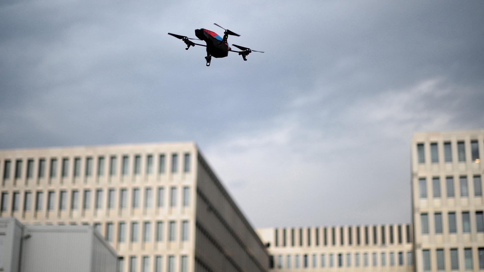 Eine von einem Demonstranten gelenkte Drohne fliegt am 29.07.2013 in Berlin während eines Protest-"Spaziergangs" vor dem Neubau des Bundesnachrichtendienstes (BND) gegen Überwachung vor grauem Himmel.