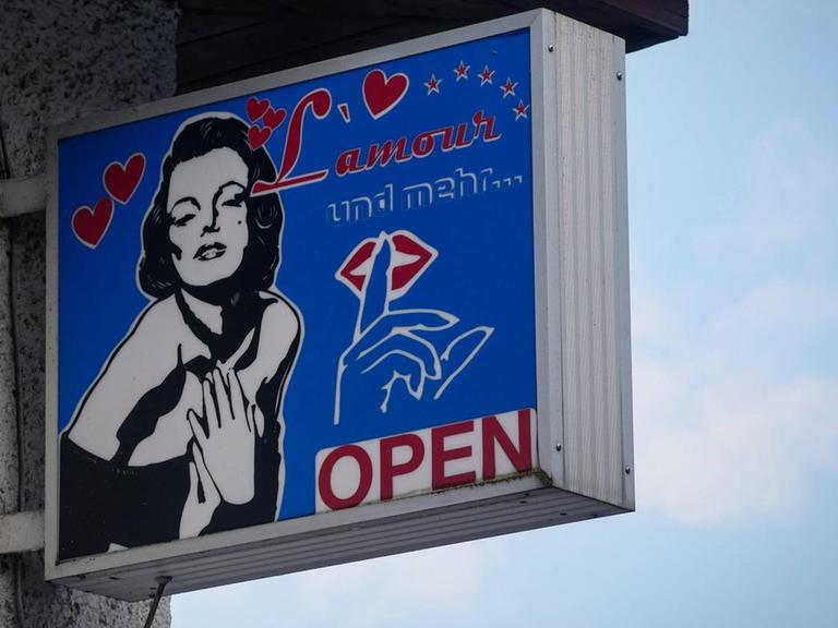 Ein Schild mit der Aufschrift "L'Amour und mehr - open" hängt an einer Hauswand