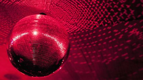 Eine Diskogugel in einem Club wird rot angestrahlt.