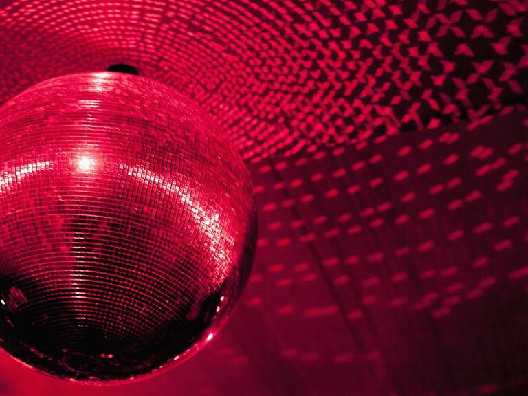 Eine Diskogugel in einem Club wird rot angestrahlt.
