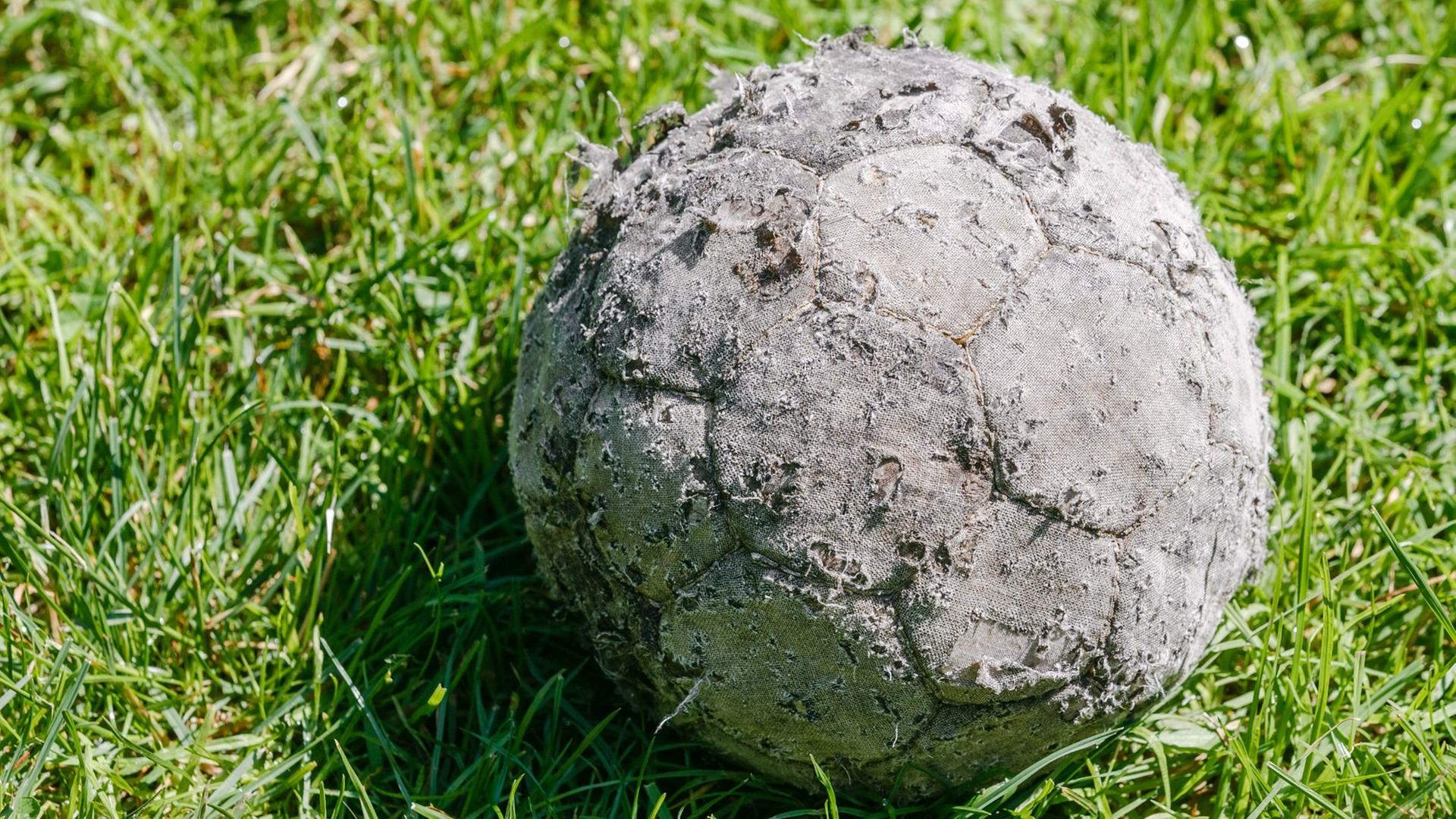 Ein alter verschlissener Fussball liegt am 07.07.2014 in Hamburg auf dem Rasen. Ein alter verschlissener Fussball liegt am 07.07.2014 in Hamburg auf dem Rasen.