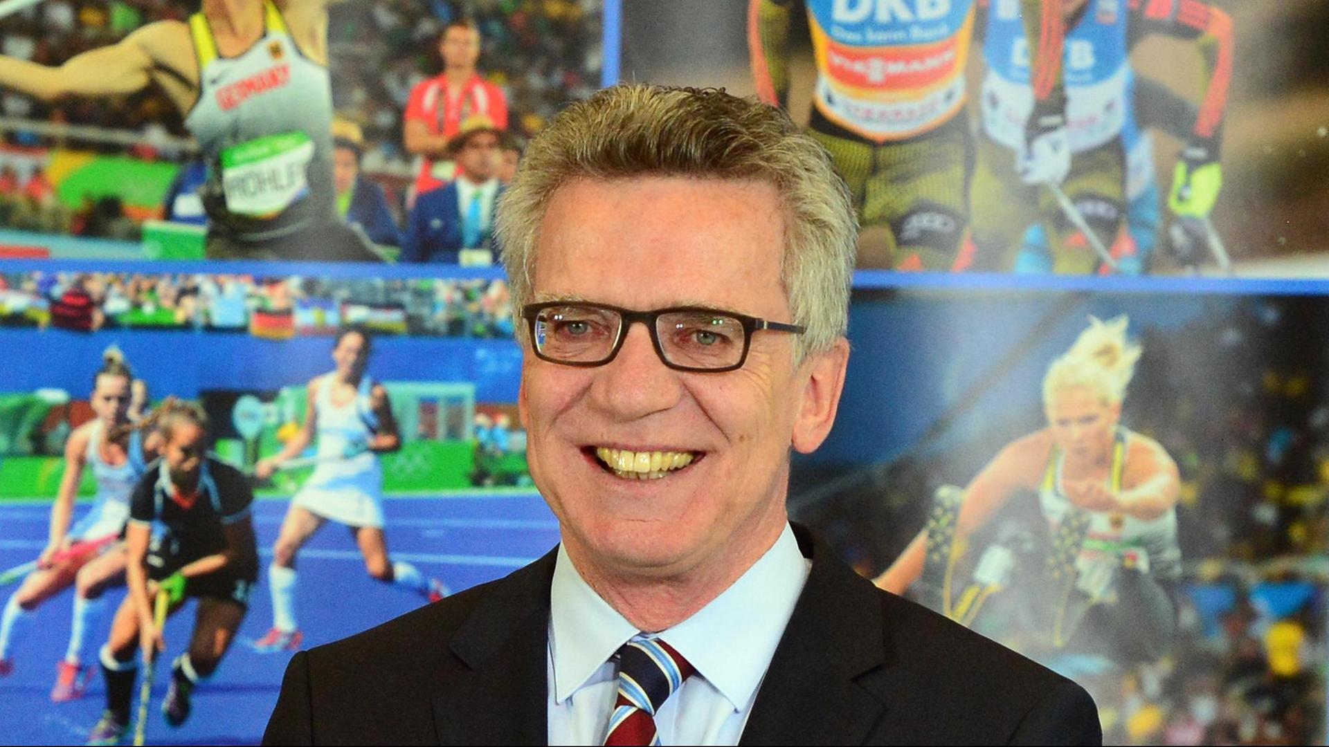 Der ehemalige Innenminister Thomas de Maiziere (CDU) steht vor einem Plakat mit Sportlern drauf. Der ehemalige Innenminister Thomas de Maiziere (CDU) steht vor einem Plakat mit Sportlern drauf.