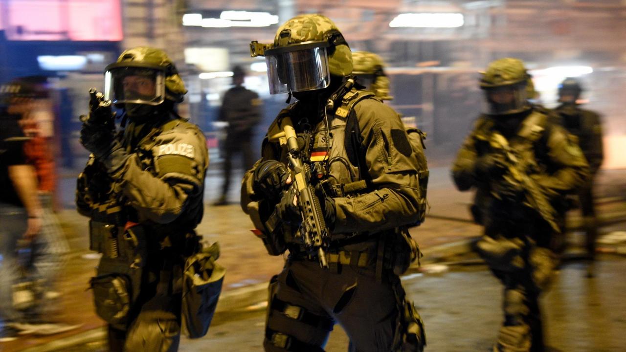 Spezialkräfte der Polizei laufen in Schutzkleidung und Gewehren durch das Schanzenviertel. Spezialkräfte der Polizei laufen in Schutzkleidung und Gewehren durch das Schanzenviertel.