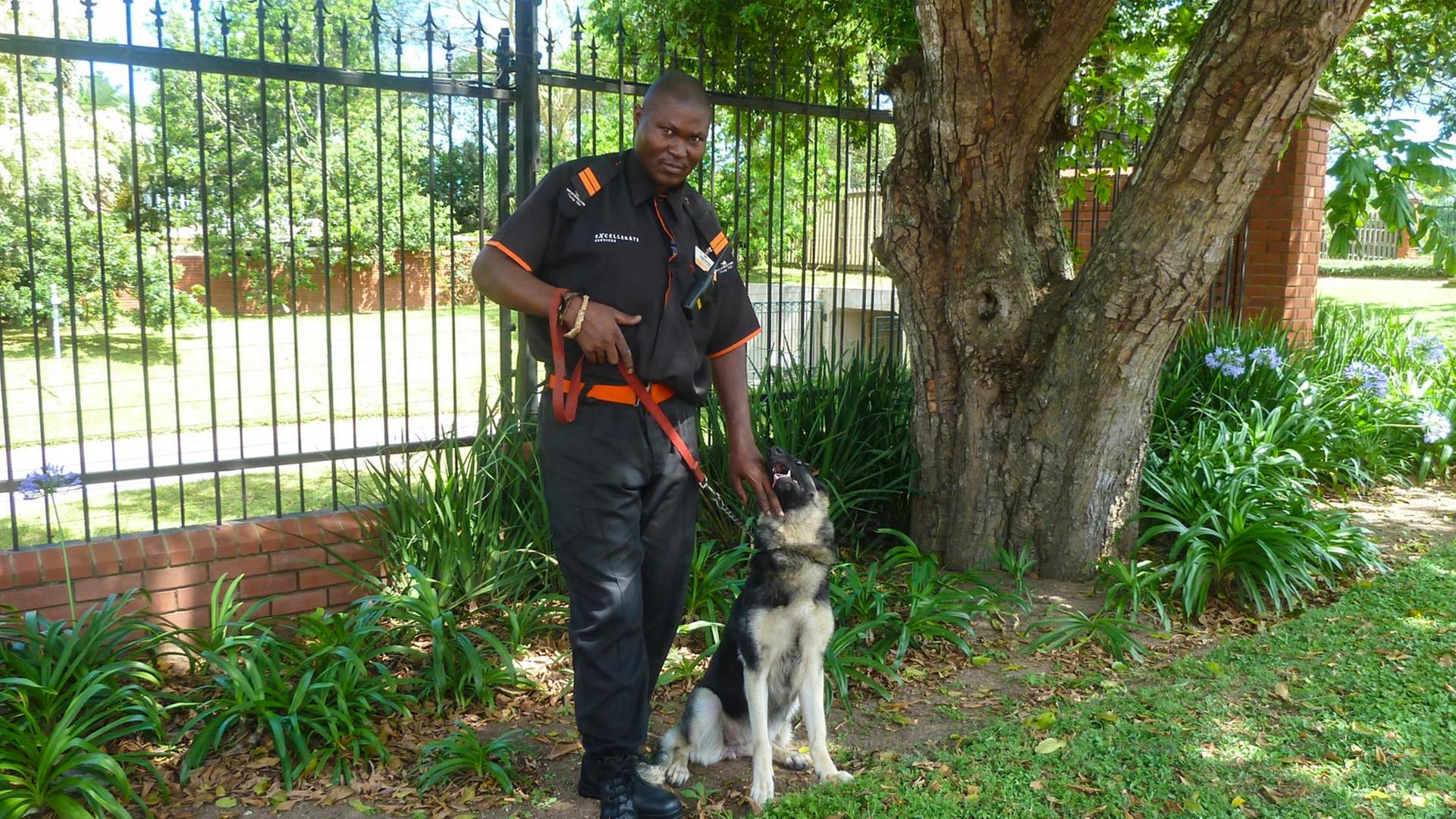 Sibusiso Gumede und sein Hund machen Patrouille am Zaun einer "Gated Community" im südafrikanischen Durban.