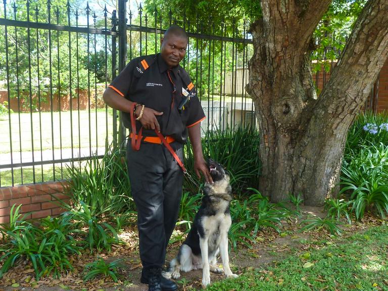 Sibusiso Gumede und sein Hund machen Patrouille am Zaun einer "Gated Community" im südafrikanischen Durban.