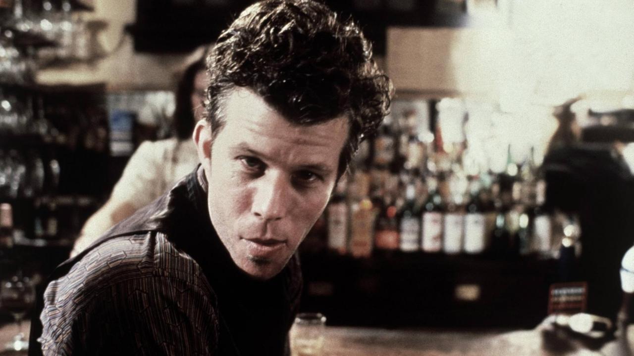Tom Waits sitzt auf einem Hocker vor einer Bar und schaut direkt in die Kamera. Die Szene stammt aus dem Film "Wolfen" von 1981. Tom Waits sitzt auf einem Hocker vor einer Bar und schaut direkt in die Kamera. Die Szene stammt aus dem Film "Wolfen" von 1981.