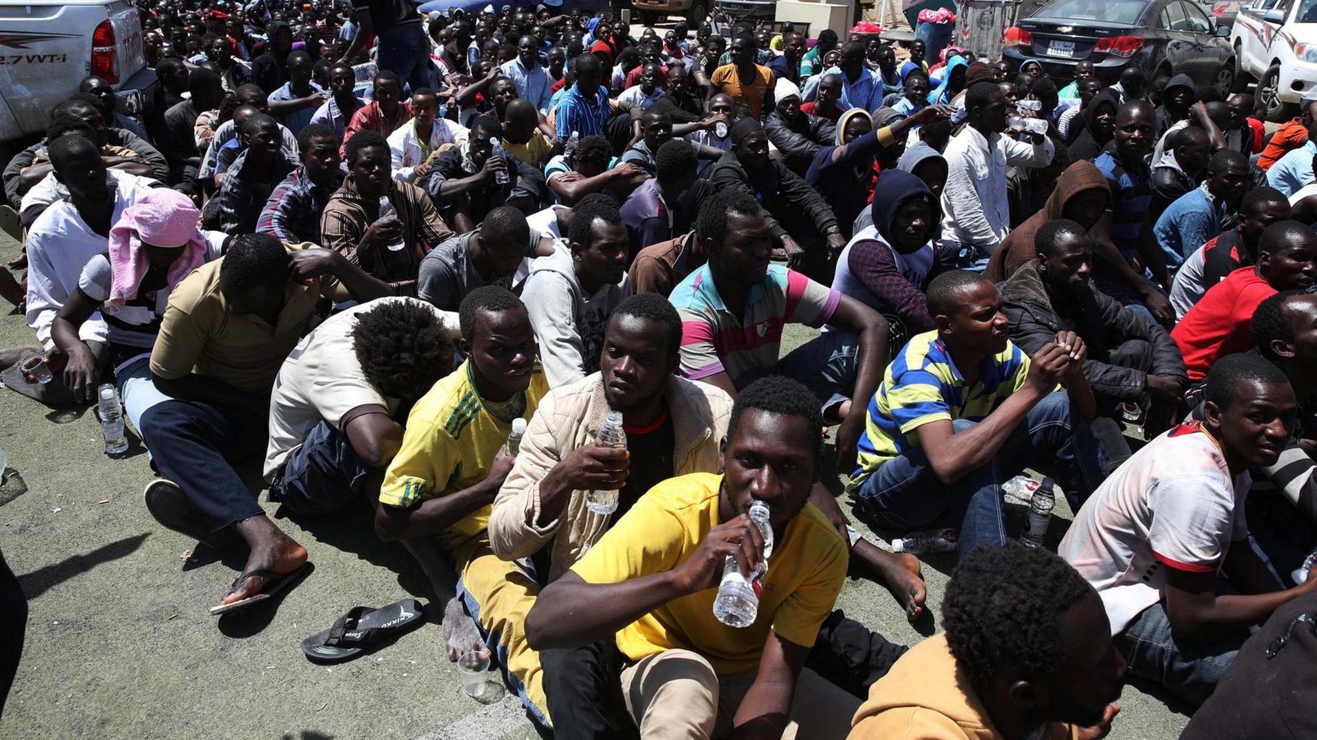 Afrikanische Flüchtlinge sitzen in Tripolis nach ihrer Verhaftung auf dem Boden. Afrikanische Flüchtlinge sitzen in Tripolis nach ihrer Verhaftung auf dem Boden.