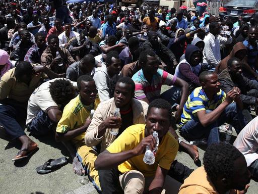 Afrikanische Flüchtlinge sitzen in Tripolis nach ihrer Verhaftung auf dem Boden.