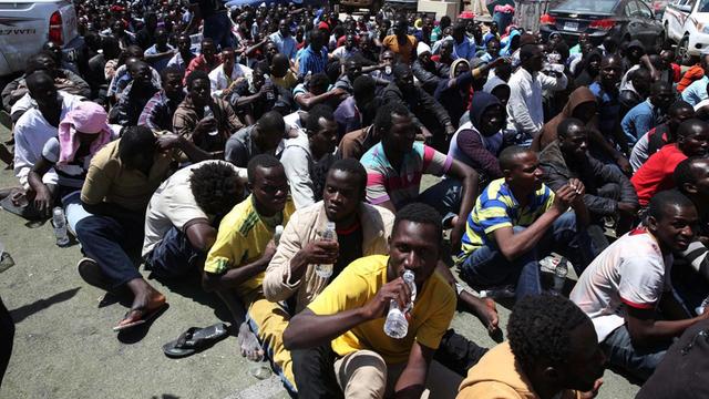 Afrikanische Flüchtlinge sitzen in Tripolis nach ihrer Verhaftung auf dem Boden.