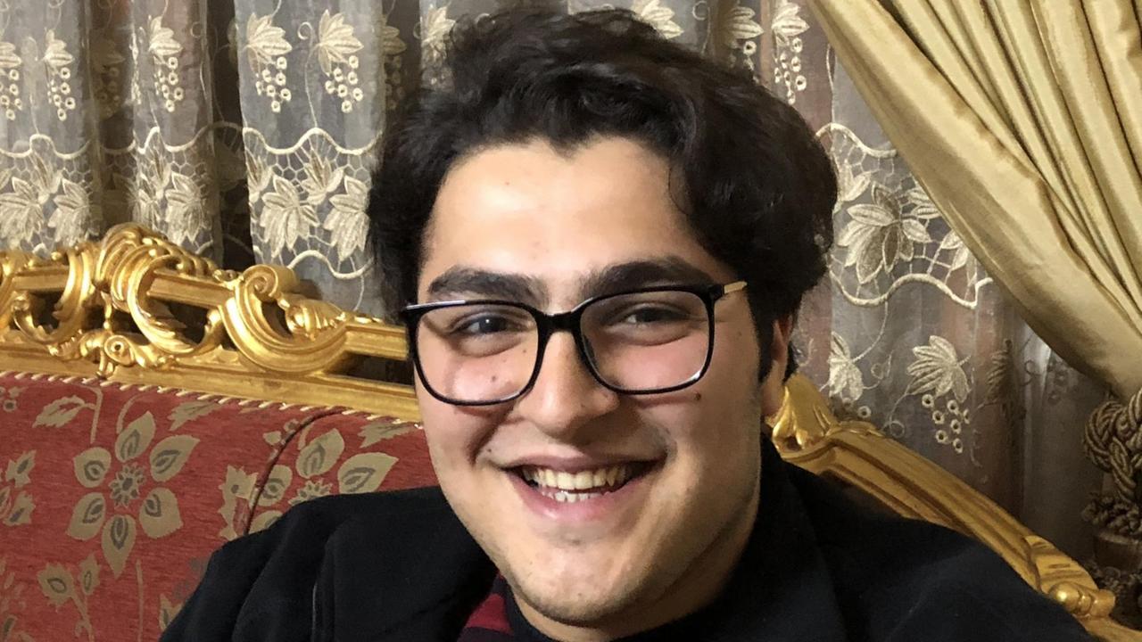 Ein junger Mann mit dunklem Haar lächelt in die Kamera Ein junger Mann mit dunklem Haar lächelt in die Kamera