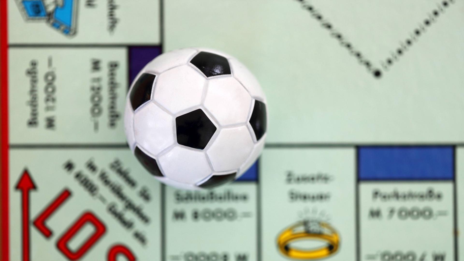 Ein kleiner Fußball liegt auf einem Monopoly-Spielbrett. Ein kleiner Fußball liegt auf einem Monopoly-Spielbrett.