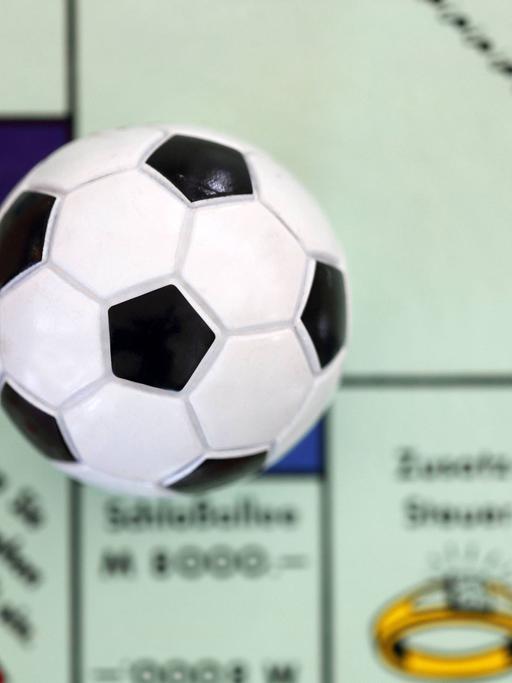 Ein kleiner Fußball liegt auf einem Monopoly-Spielbrett.