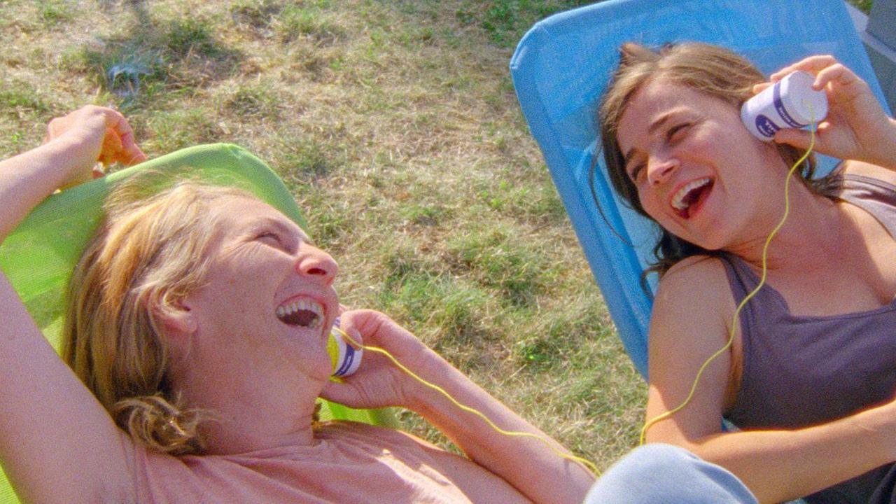 Zwei Frauen sitzen auf Liegestühlen und lachen Zwei Frauen sitzen auf Liegestühlen und lachen