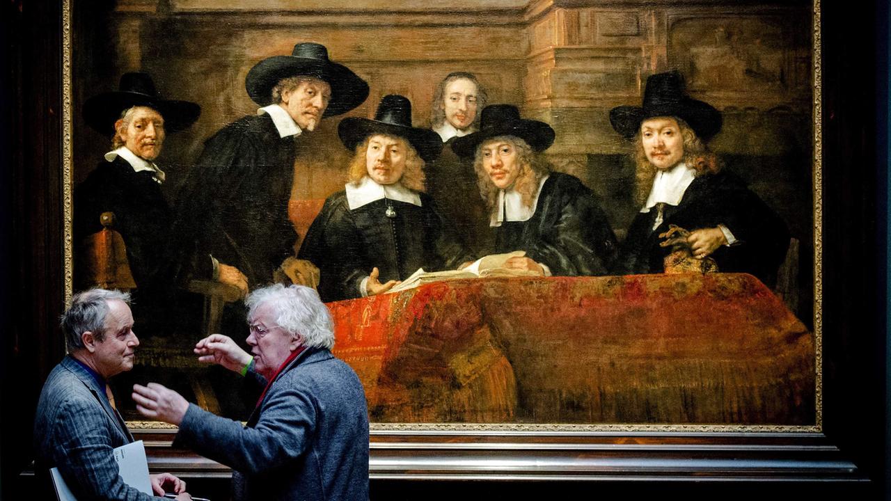 Zwei Männer diskutieren vor Rembrandts "The Steelmasters", das in der Ausstellung "Der späte Rembrandt" im Amsterdamer Reichsmuseum gezeigt wird. Zwei Männer diskutieren vor Rembrandts "The Steelmasters", das in der Ausstellung "Der späte Rembrandt" im Amsterdamer Reichsmuseum gezeigt wird.
