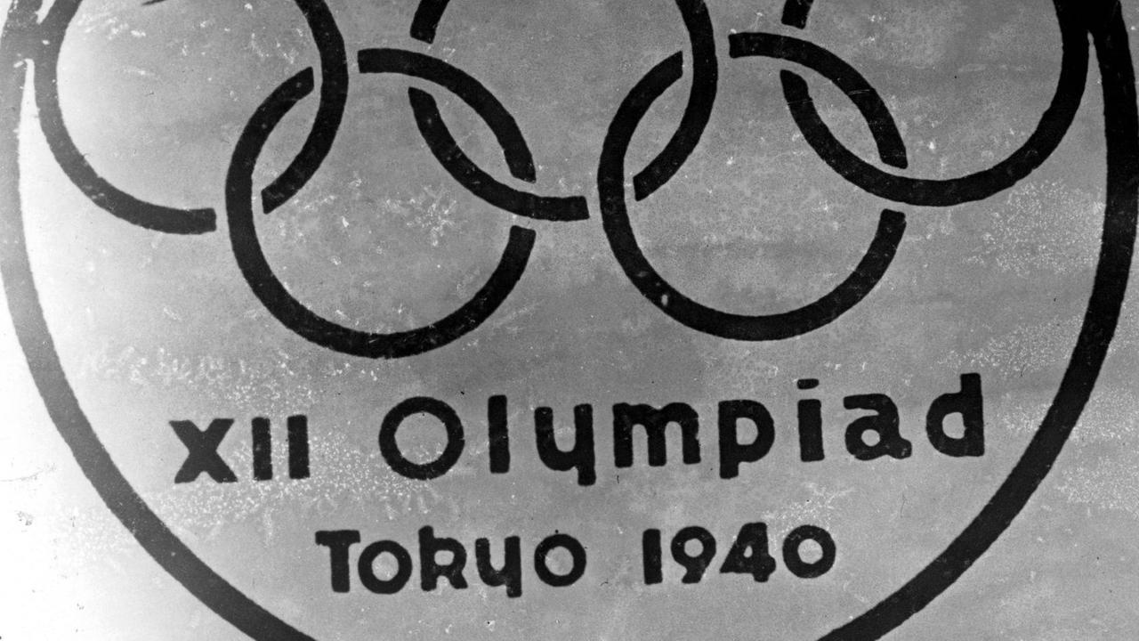 Ein altes Embelem mit den Olympischen Ringen vor dem Berg Fuji und der Inschrift XII Olympiad Tokyo 1940 Ein altes Embelem mit den Olympischen Ringen vor dem Berg Fuji und der Inschrift XII Olympiad Tokyo 1940