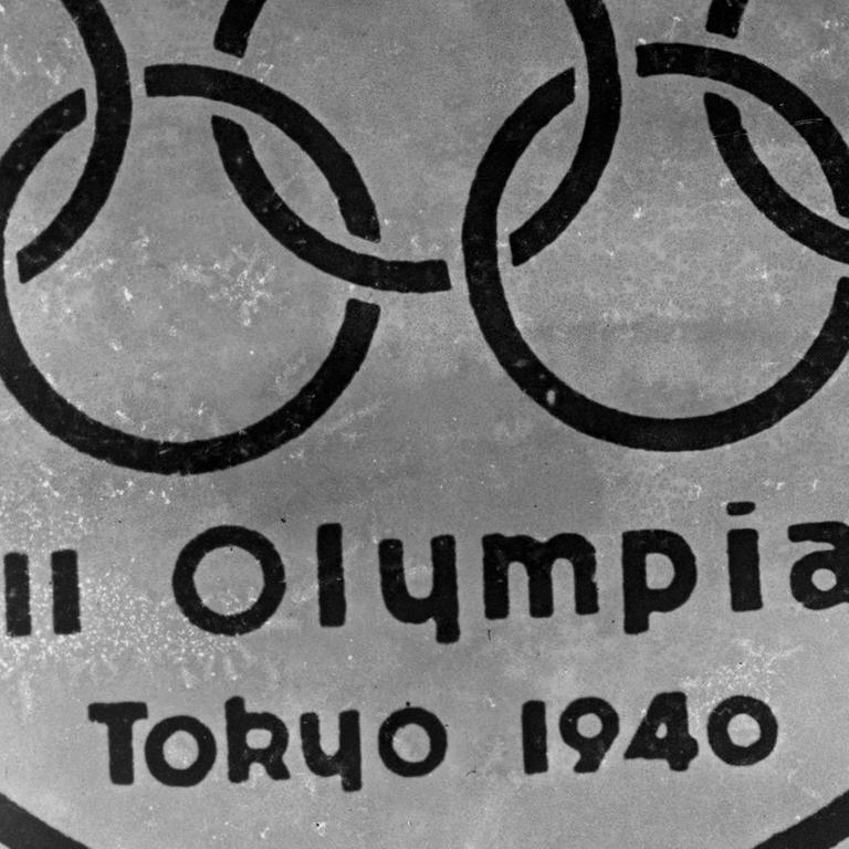 Ein altes Embelem mit den Olympischen Ringen vor dem Berg Fuji und der Inschrift XII Olympiad Tokyo 1940