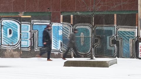 In der Innenstadt von Detroit gehen bei Schneefall Personen an einem Graffiti vorbei.