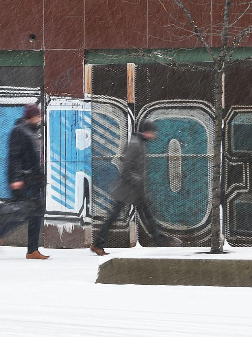In der Innenstadt von Detroit gehen bei Schneefall Personen an einem Graffiti vorbei.