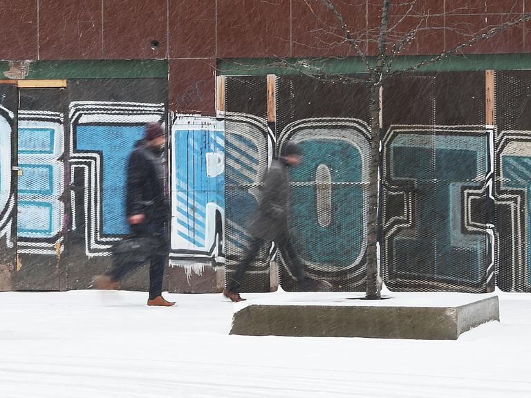 In der Innenstadt von Detroit gehen bei Schneefall Personen an einem Graffiti vorbei.