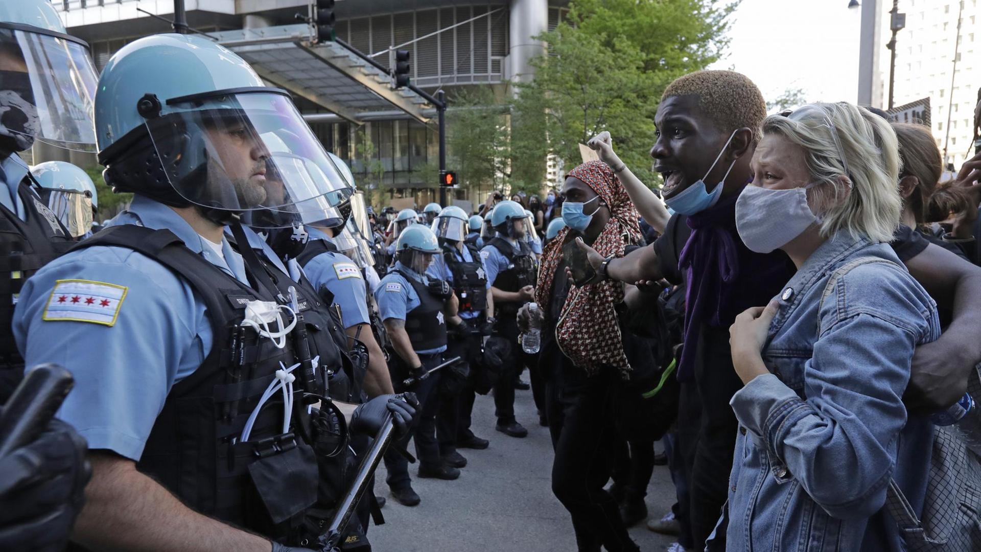 Mehrere Teilnehmer einer Demonstration stehen in Chicago einer Gruppe von Polizisten gegenüber Mehrere Teilnehmer einer Demonstration stehen in Chicago einer Gruppe von Polizisten gegenüber