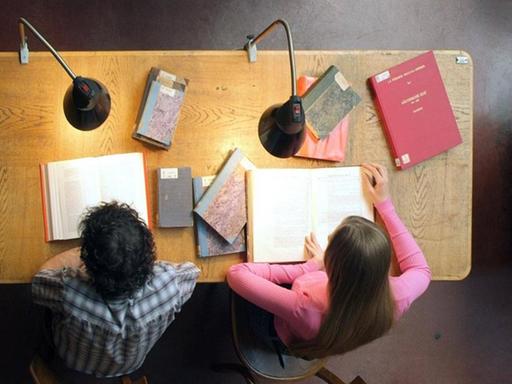 Studenten sitzen an Tisch in Universitätsbibliothek, Blick von oben.