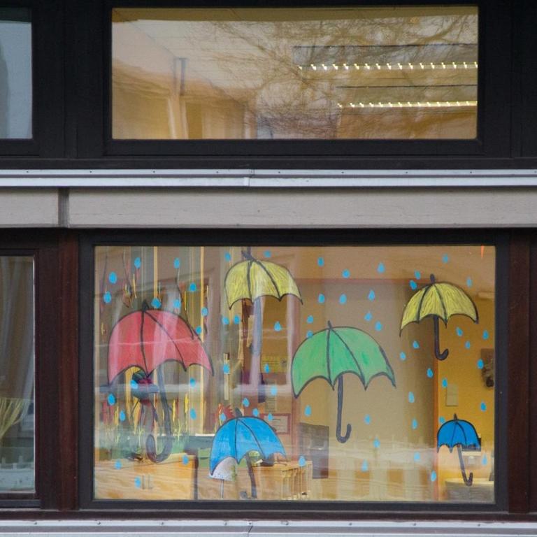 Das Fenster eines Klassenzimmers ist mit bunten Regenschirmen dekoriert. 