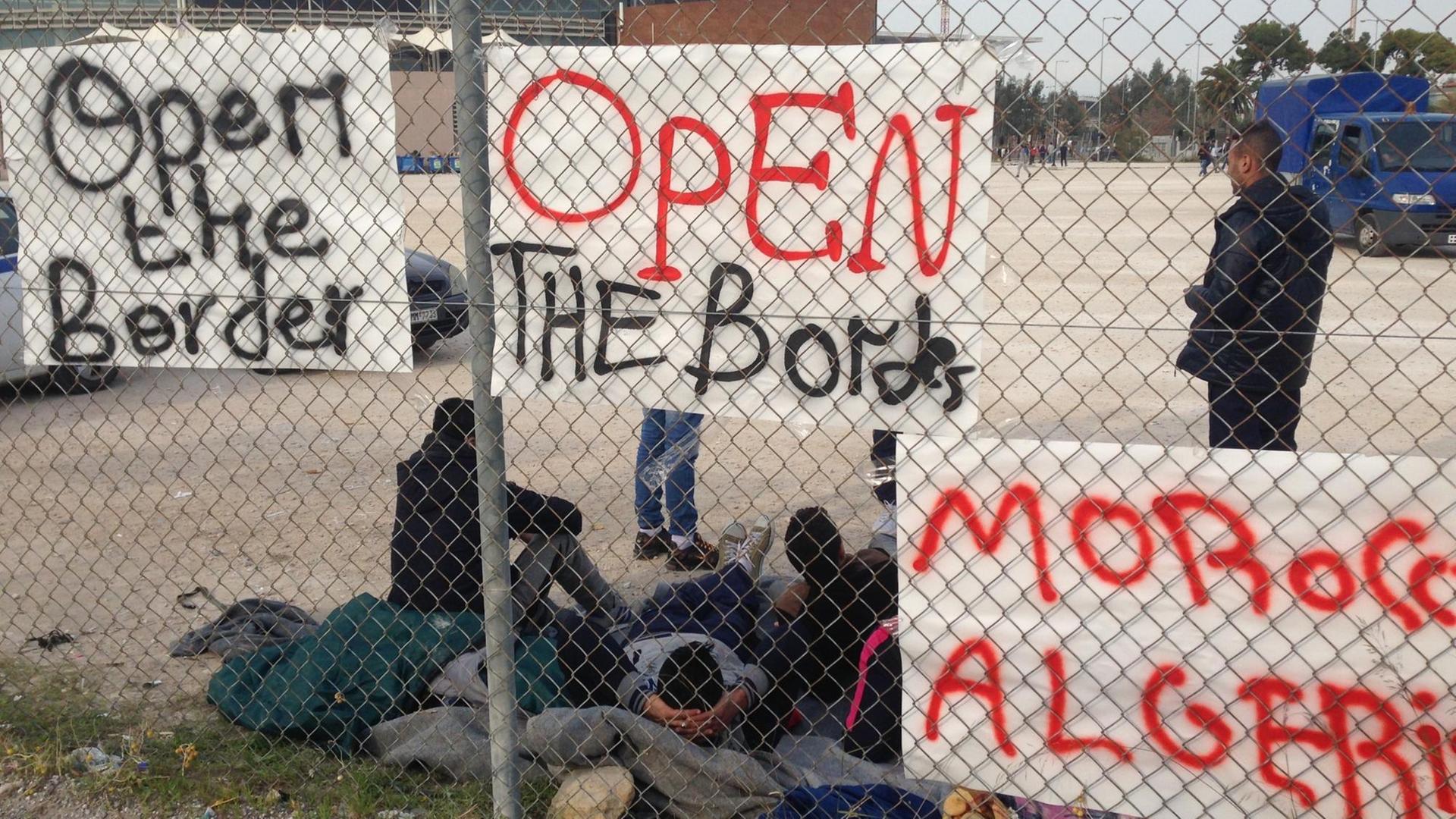 Ein Zaun mit einigen der Plakaten und den Migranten aus Marokko. Ein Zaun mit einigen der Plakaten und den Migranten aus Marokko.